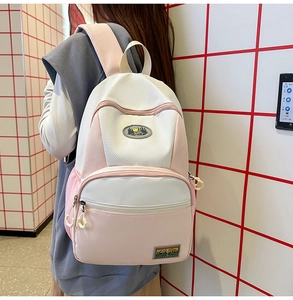 Detail of pink and white nylon backpack featuring honeycomb texture and outdoor patches
