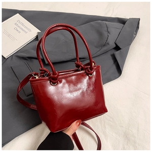 Close-up view of a vintage red glossy bucket bag featuring stylish double top handles
