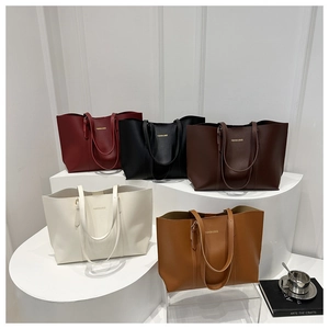 Multiple colors of large matte leather tote bags shown on white display stands