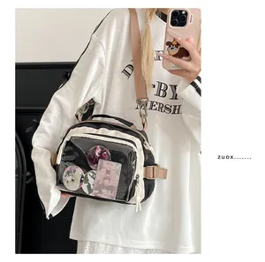 Détail du sac Ita bicolore avec fenêtre transparente affichant des badges anime