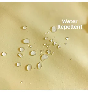 Macro shot of bright yellow water repellent fabric with beads of water on the surface