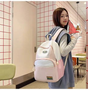 Pink and white patchwork nylon backpack with mesh details and front zipper pocket