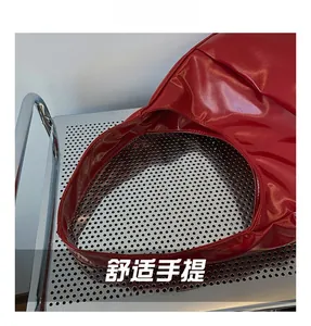 Detail of red glossy patent leather shoulder bag showing the wide comfortable handle