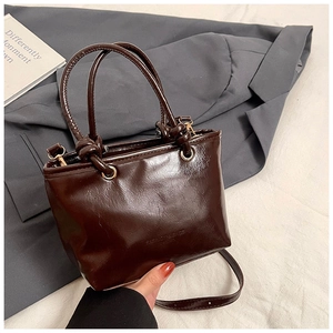 Detailed close-up of dark brown glossy leather bucket bag with elegant knot handle design