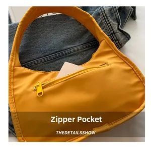 Detail view of the bright yellow shoulder bag featuring a functional front zipper pocket
