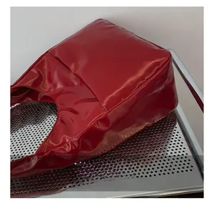 Detailed close-up showing precision stitching on the red glossy leather handbag base