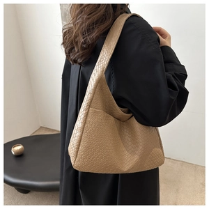 Detail of large beige woven tote bag showing texture and crescent hobo shape on shoulder