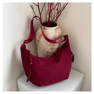 Détail du sac bandoulière bordeaux avec fermeture éclair à nœud tressé et tissu nylon