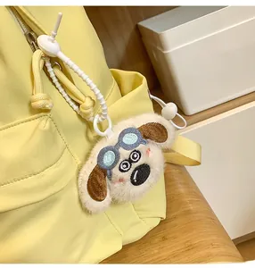Close-up of cute plush dog keychain with goggles attached to a yellow backpack
