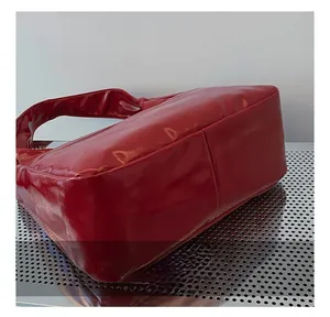Detail showing high-gloss red patent leather texture and minimalist shoulder strap design