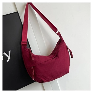Détail du sac demi-lune en nylon bordeaux avec bandoulière réglable et tirette tressée