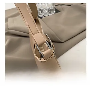 Detailed macro view of high-quality metal D-ring and stitching on beige shoulder bag