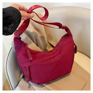 Détail du sac bandoulière demi-lune bordeaux avec fermeture éclair tissée et sangle