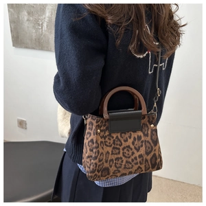 Detail of leopard print tote bag with dark wood handles and removable shoulder strap