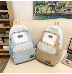 Detail of two lightweight nylon backpacks in blue and khaki with mountain patches