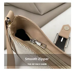Close-up of high-quality smooth metal zipper and textured fabric detail on beige baguette bag
