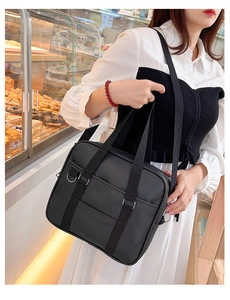 Japanese style black collegiate faux leather handbag shown on a model in a cozy cafe setting