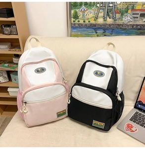 Detail of nylon backpacks in pink and black featuring multi-pocket design and mountain badges