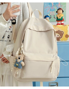 Detail of off-white backpack showing waterproof fabric texture and cute bear charm