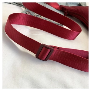 Détail d'une bandoulière en nylon rouge avec boucle réglable pour les grands sacs