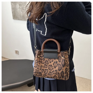 Chic leopard print tote bag with wooden handles styled as a shoulder bag on a model