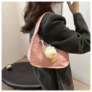 Pink crescent underarm bag with cute plush duck pendant shown in a fashion styling context