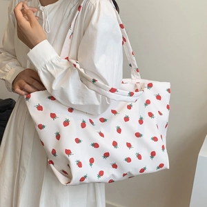 Grand sac cabas en toile blanche avec imprimé fraises rouges porté par une femme