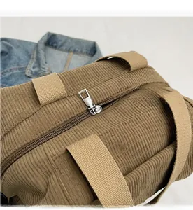 Detail view of the brown corduroy tote bag showing the smooth metal zipper and strap