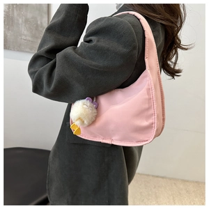 Pink crescent shoulder bag with white plush duck charm shown on a model's shoulder