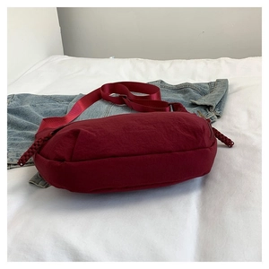 Détail d'un sac demi-lune en nylon bordeaux avec bandoulière réglable et tirette en corde