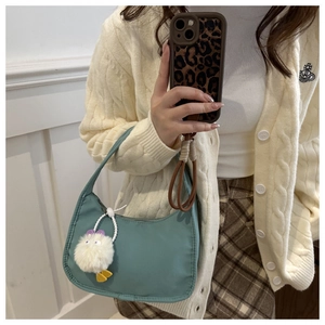 Close-up of light cyan nylon crescent bag with cute white plush monster charm