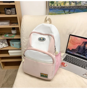 Close-up of pink and white nylon backpack with mountain patches and mesh side pocket
