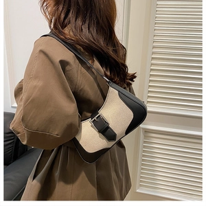 Model wearing a retro hobo underarm bag in beige canvas and black leather patchwork