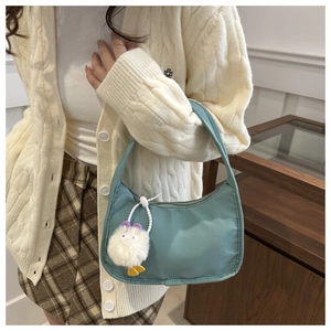 Minimalist light blue crescent underarm bag with cute white plush charm on a model