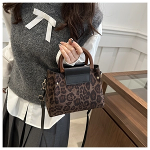 Detail of leopard print tote bag with brown wooden circular handle and gold hardware