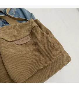 Macro detail of brown corduroy tote bag showing vertical ribbed fabric texture and logo