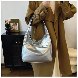Silver metallic hobo bag worn by a model in a cozy lifestyle indoor home setting