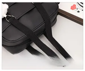 Close-up of black leather bag with woven handle and cute white plush charm detail