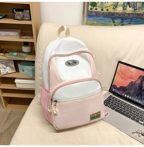 Close-up of pink and white nylon backpack with side mesh pockets on a cozy sofa