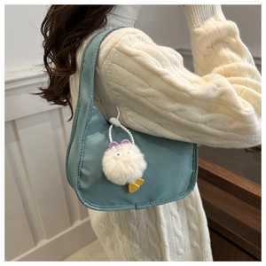 Minimalist green nylon underarm bag with a white plush charm shown on person