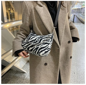 Detail of plush zebra print tote bag with adjustable black strap and silver chain accessory