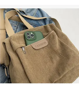 Close-up of khaki corduroy tote with zipper pocket and adjustable cream strap