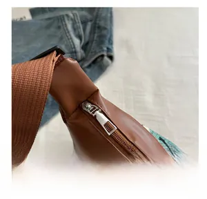Close-up of smooth silver metal zipper and brown leather texture on canvas tote bag