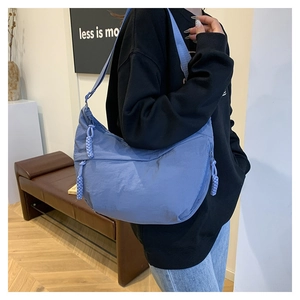 Détail du sac bandoulière gris-bleu avec une tirette de fermeture éclair en corde tressée