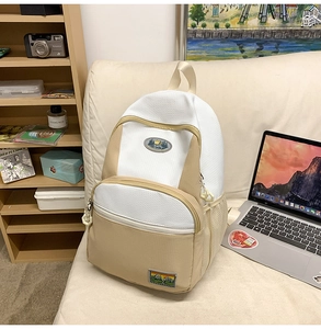 Close-up of a nylon backpack on a sofa showing outdoor-style mountain logo patches