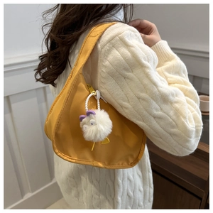 Detailed shot of yellow crescent nylon bag with white plush charm and sleek stitching