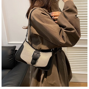 Detail of canvas and leather patchwork baguette bag with decorative buckle shown on shoulder