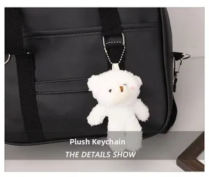Close-up of a white plush bear charm with a metal bead chain on a black commuter bag