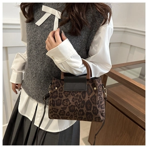 Detail of leopard print tote bag with vintage round wooden handles and black leather flap