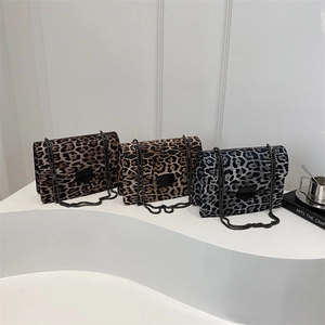 Drei Umhängetaschen mit Leopardenmuster in Braun und Blau auf einem weißen Display-Ständer